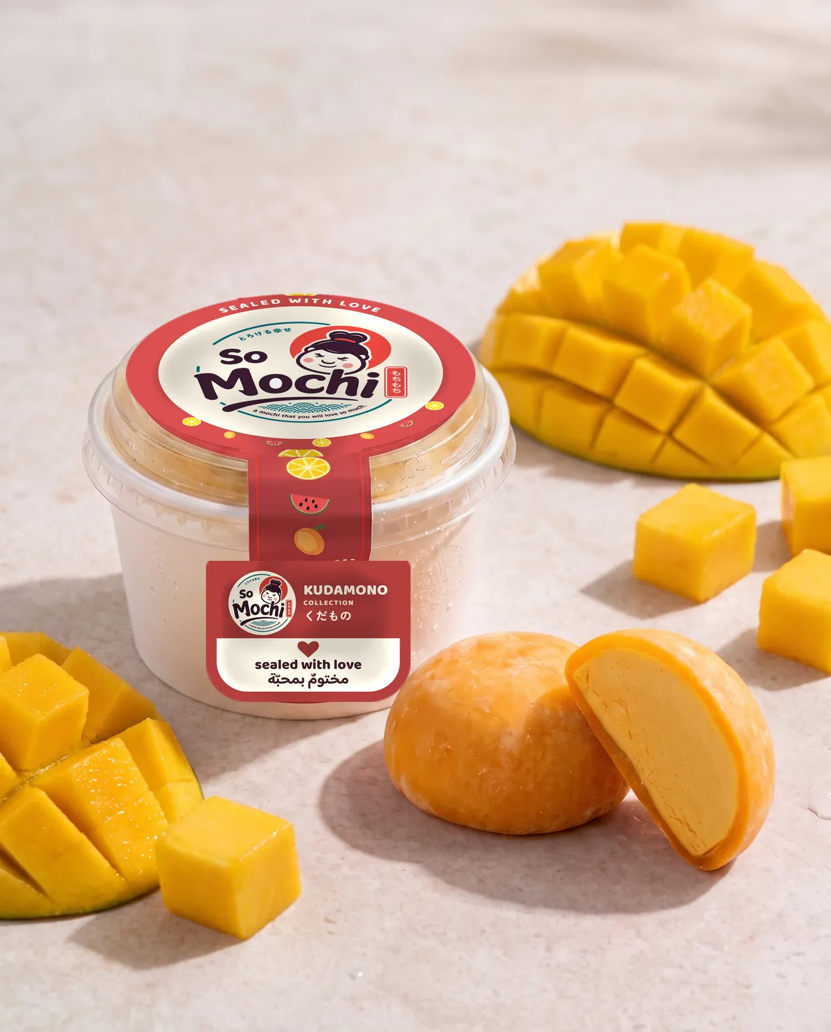 Jumbo Mango mochi, whole and cut open, beside its sealed So Mochi cup