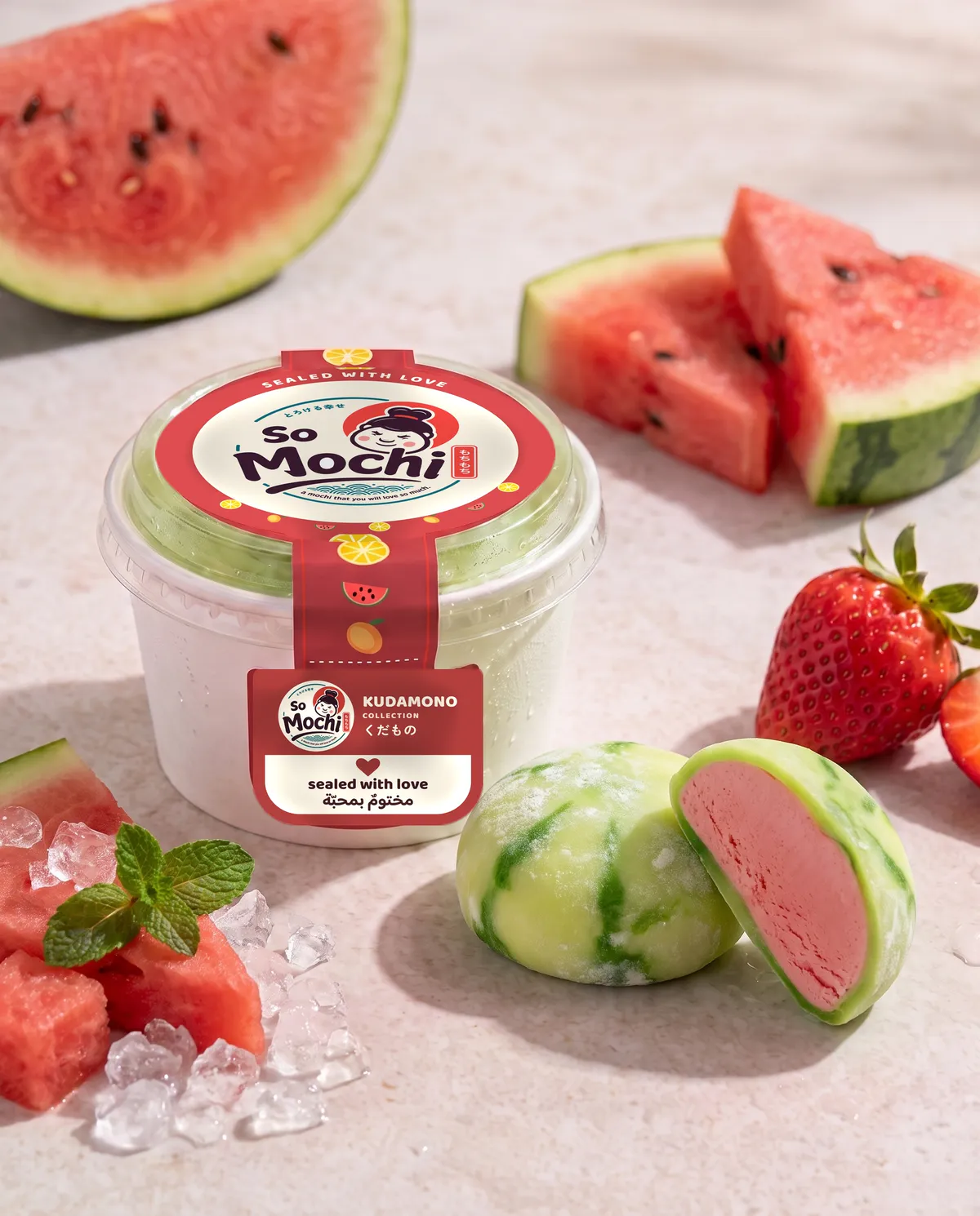 Jumbo Watermelon mochi, whole and cut open, beside its sealed So Mochi cup